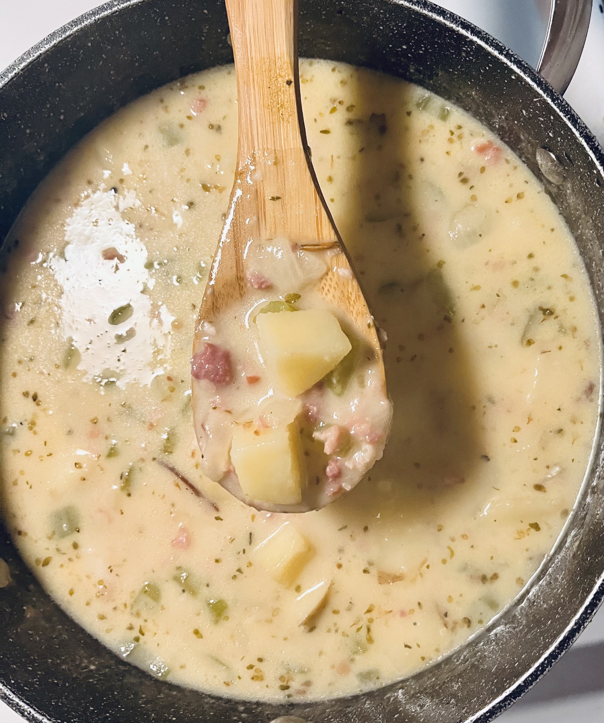 Cooked ham and potato soup in a black soup pot